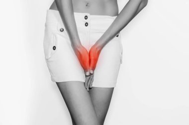 Beyaz mini etek ayakta bacaklar arasında elleri genç kadın için beyaz arka plan izole bir tuvalet ihtiyacı var. Kadın sağlığı, kadın hastalıkları.