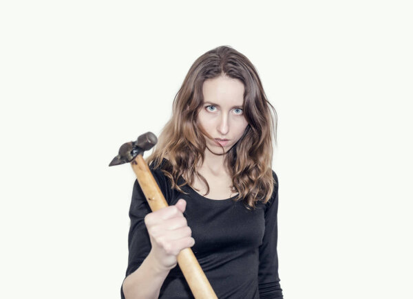 Beautiful girl in a black dress holding a hammer in hand. Threat, violence, threatens to strike. Hard work, exploitation, release.