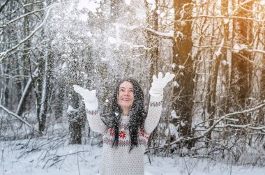 Karla kaplı ormanda bir kadın kar arka plan ağaçta ellerini atar. Kış eğlence, dinlenme, eğlence