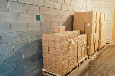 Beton duvar yakınındaki ambarındaki palet üzerinde karton kutular