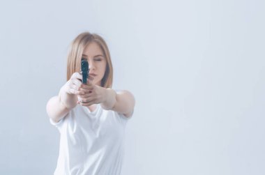 Onun elinde bir silah tutan genç güzel kız. Kameraya amaçları.