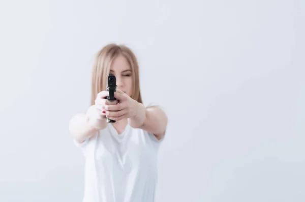 Menina bonita jovem segurando uma arma em suas mãos. Objectivos para a câmara . — Fotografia de Stock