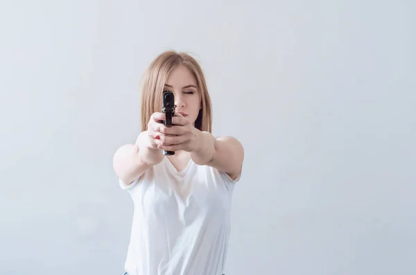 Menina bonita jovem segurando uma arma em suas mãos. Objectivos para a câmara . — Fotografia de Stock