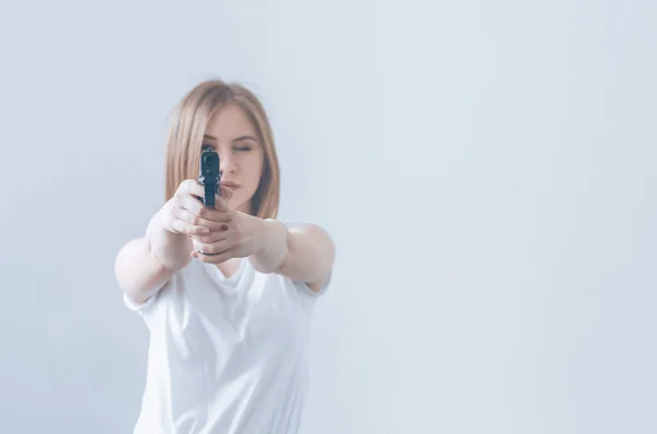 Menina bonita jovem segurando uma arma em suas mãos. Objectivos para a câmara . — Fotografia de Stock