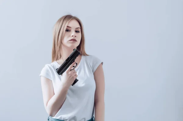 Menina bonita jovem segurando uma arma em suas mãos. Pistola levantada para o rosto . — Fotografia de Stock