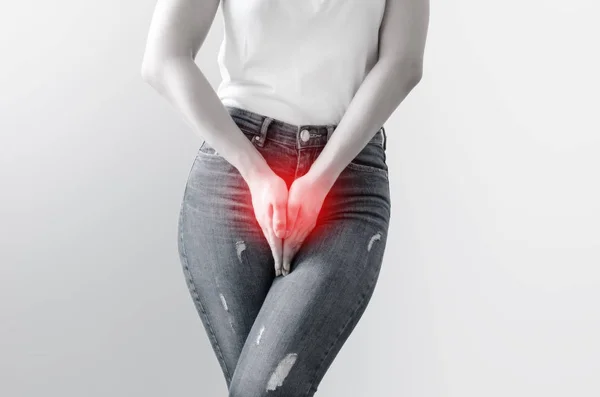 Young woman in jeans standing with her hands between legs — Stock Photo, Image