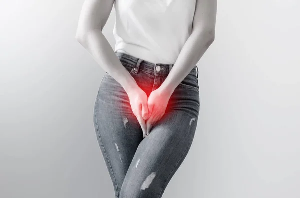 Young woman in jeans standing with her hands between legs — Stock Photo, Image