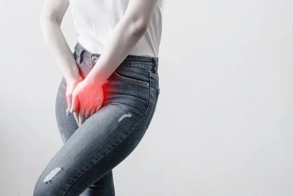 Young woman in jeans standing with her hands between legs — Stock Photo, Image