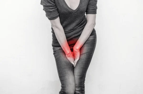 Young slim girl in jeans holds hands pressed between her legs. P — Stock Photo, Image