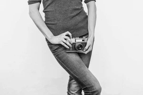 Девушка в джинсах держит старую винтажную кинокамеру на бедрах . — стоковое фото