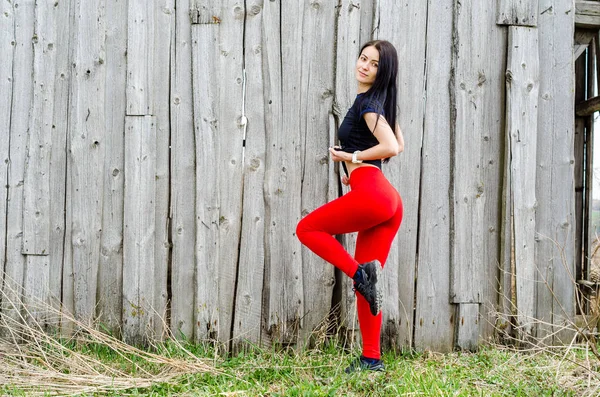 Schöne junge athletische Mädchen in roten Leggings auf dem Hintergrund — Stockfoto