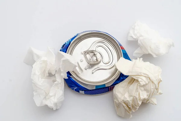 Geplet geperst aluminium kan van een koolzuurhoudende drank met verkruimelde vellen papier. Vervuiling, afval, ecologie — Stockfoto