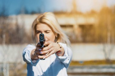 Woman with a gun aims at the camera