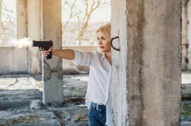 Woman in white shirt in an abandoned building shoots a pistol