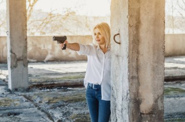 Woman in white shirt in an abandoned building shoots a pistol