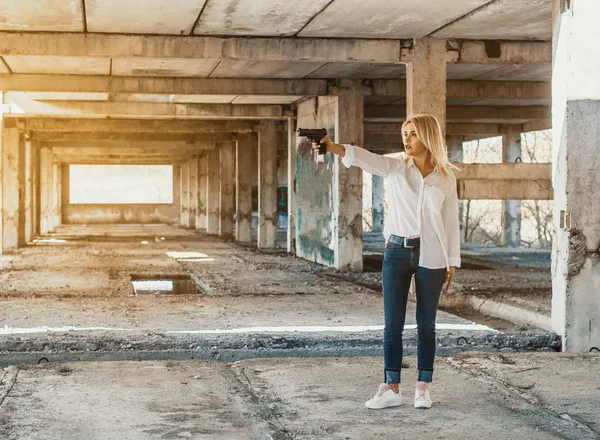 Γυναίκα με λευκό πουκάμισο στέκεται σε ένα εγκαταλελειμμένο κτίριο, πυροβολεί ένα g — Φωτογραφία Αρχείου