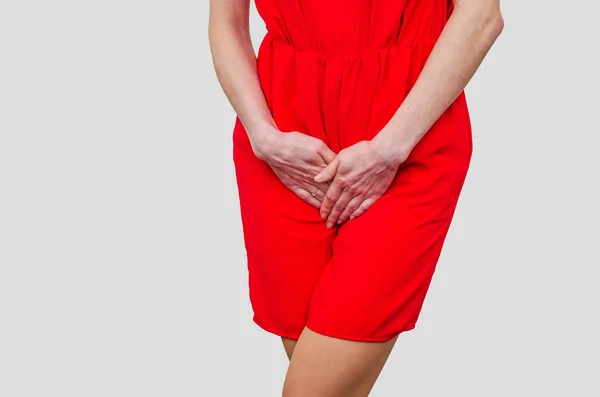 Žena v červených šatech drží ruce mezi nohama. Zkušenosti pa — Stock fotografie