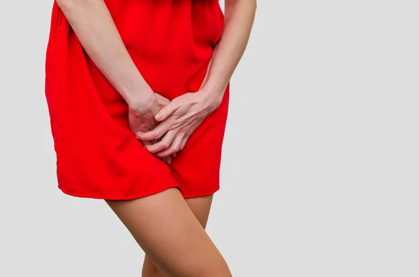 Kobieta w czerwonej sukience trzymająca się za ręce między nogami. Doświadczenia pa — Zdjęcie stockowe