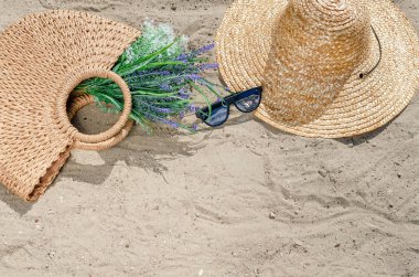 Bea üzerinde kum üzerinde yatan bir hasır şapka ve çanta ile güneş gözlüğü