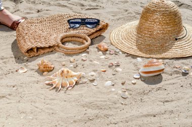 Bir hasır şapka, çanta ve kabukları ile güneş gözlüğü t kum üzerinde yalan
