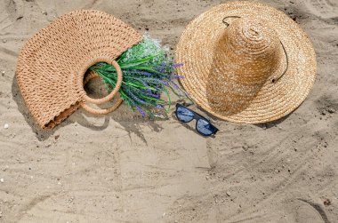 Bea üzerinde kum üzerinde yatan bir hasır şapka ve çanta ile güneş gözlüğü
