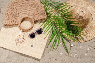 Hasır şapka ve güneş gözlüğü ile palmiye yaprakları kum üzerinde olmak