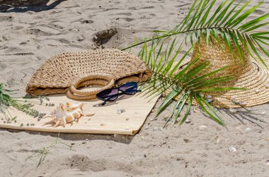 Hasır şapka ve güneş gözlüğü ile palmiye yaprakları kum üzerinde olmak