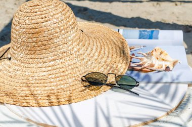 Hasır şapka ve güneş gözlüğü bir deniz kabuğu ve whi bir dergi ile