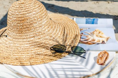Hasır şapka ve güneş gözlüğü bir deniz kabuğu ve whi bir dergi ile