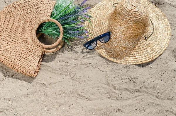 Gafas de sol con sombrero de paja y bolsa tumbada en la arena sobre el bea — Foto de Stock