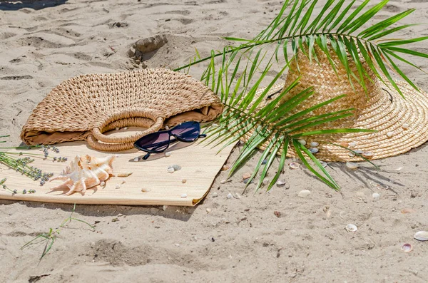Hasır şapka ve güneş gözlüğü ile palmiye yaprakları kum üzerinde olmak