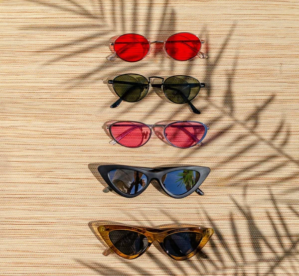 Diferentes gafas de sol en un respaldo de paja en el sol. Escena de verano — Foto de Stock