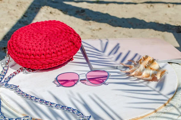 Small red women 's handbag, pink sunglasses, magazine, cockleshel — стоковое фото