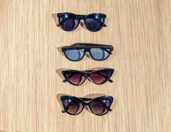 Různé sluneční brýle na slámově podložce na slunci. Letní scéna — Stock fotografie