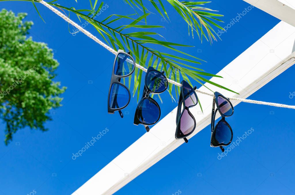 Different sunglasses hanging on a white rope on a background of 