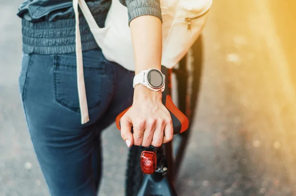 Χέρι κορίτσι με λευκό αθλητικό ρολόι Smart σε σέλα ποδηλάτου — Φωτογραφία Αρχείου