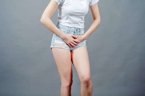 Mujer vestida con pantalones cortos de mezclilla presiona sus manos a la baja — Foto de Stock