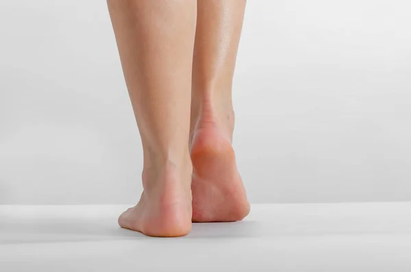 Female feet, feet stand on a white background, Smooth skin, foot care.