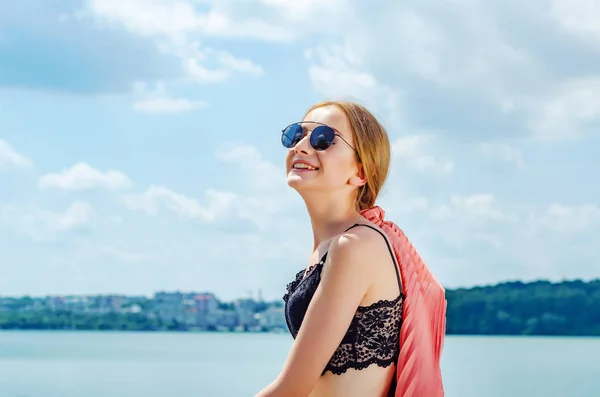 Jovem retrato menina em óculos de sol fundo céu com nuvens e água do lago — Fotografia de Stock
