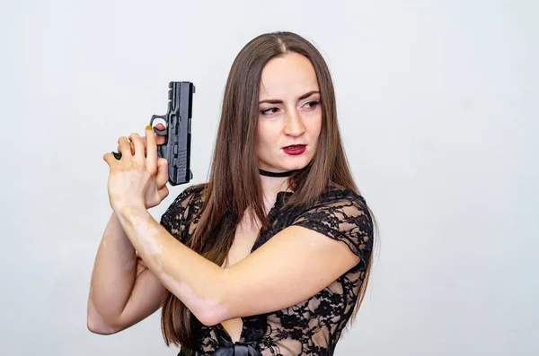 갈색 머리를 가진 레이스 탑을 입은 여성은 손에 총을 들고, 조준 — 스톡 사진