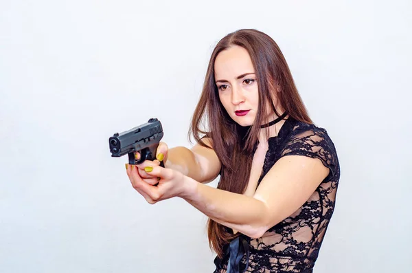 Mulher em um top de renda com cabelo castanho segura uma arma na mão, apontar — Fotografia de Stock