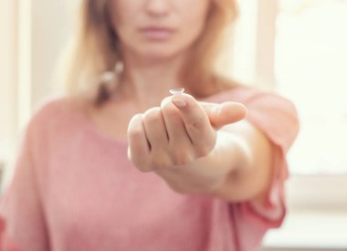 Kadın uzatılmış parmağın ucunda kontakt lens gösterir. Optik