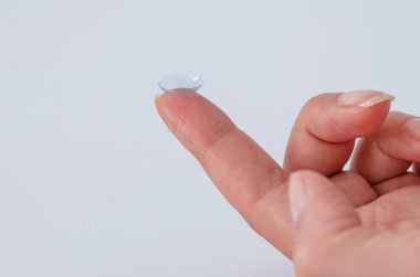 Bir kadının parmak ucunda kontakt lens yakın çekim.