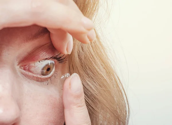 Kvinnan infogar en kontaktlins i ögat. Närbild, inhemsk scen. Optik, vision, optiska instrument — Stockfoto