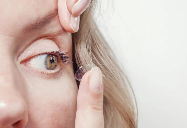 Mujer inserta un lente de contacto en el ojo . — Foto de Stock