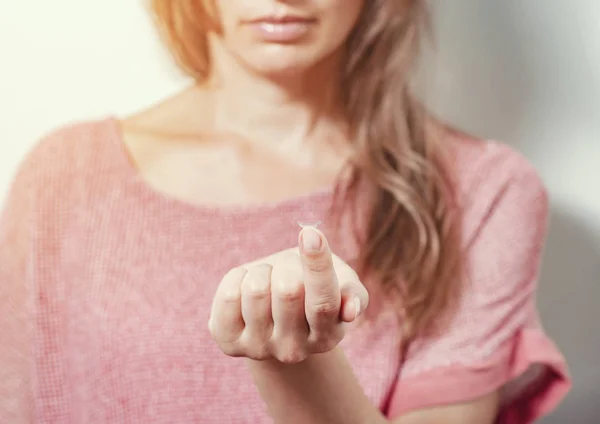 女性は伸ばされた指の先端にコンタクトレンズを示す。光学 — ストック写真