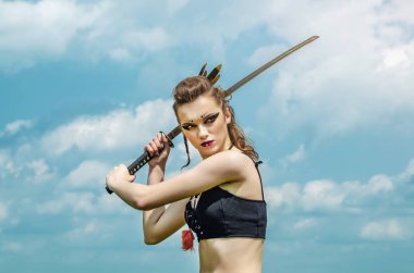 Elinde kılıç ile gökyüzü arka plan üzerinde makyaj amazon savaş boya boyama ile kız portresi