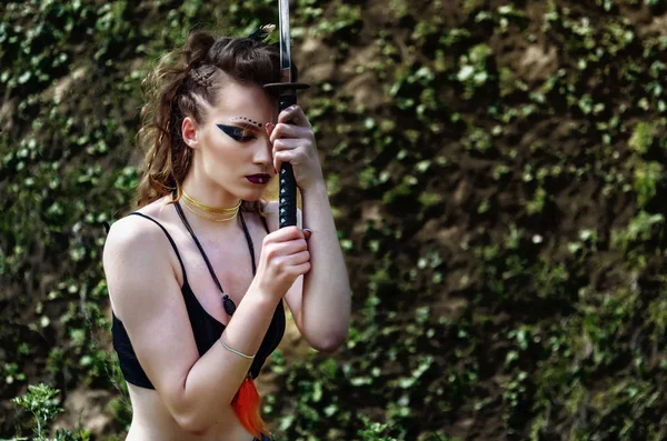 Amazon makyaj ile Savaşçı kız kollarında bir kılıç tutar