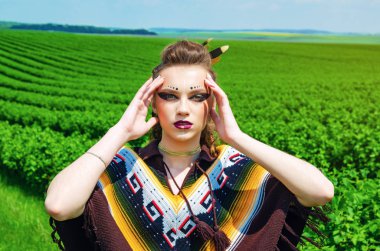 Makyaj Amazon, Viking, agresif savaş boyası ile bir kız portresi. Arka plan gökyüzünde bir poncho giymiş, yeşil alan