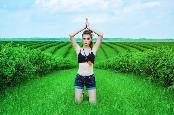 Viking aggressive makeup girl cosplay in a green wheat field. Kneeling, praying to the ancient gods. Paganism, feminism, independence, tribe.